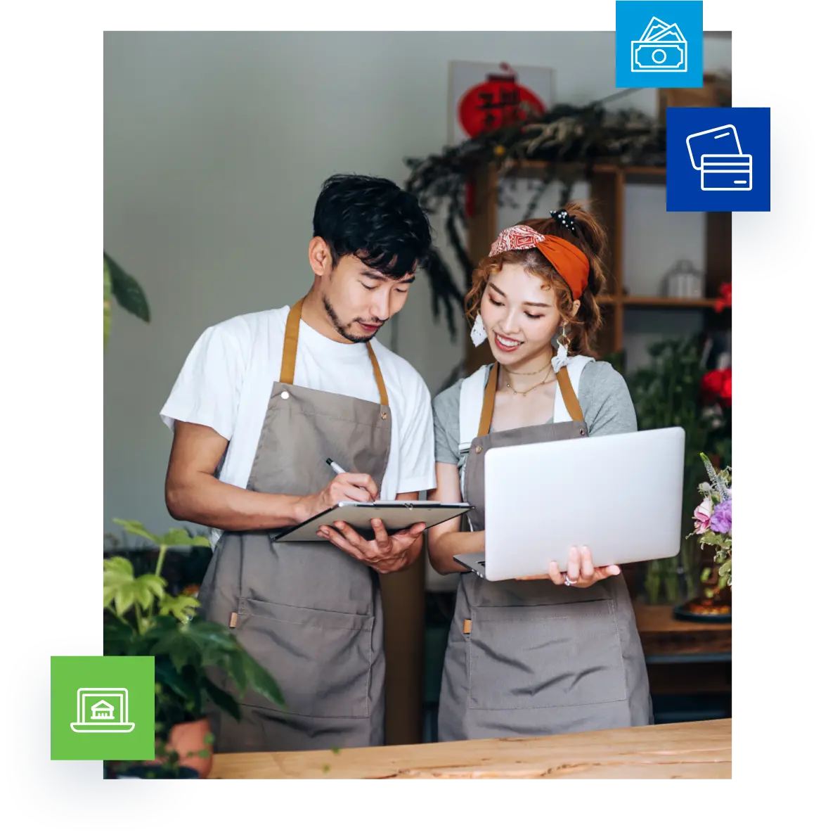 Young Asian couple, owners of small business flower shop, using laptop and working together in the shop against flowers and plants