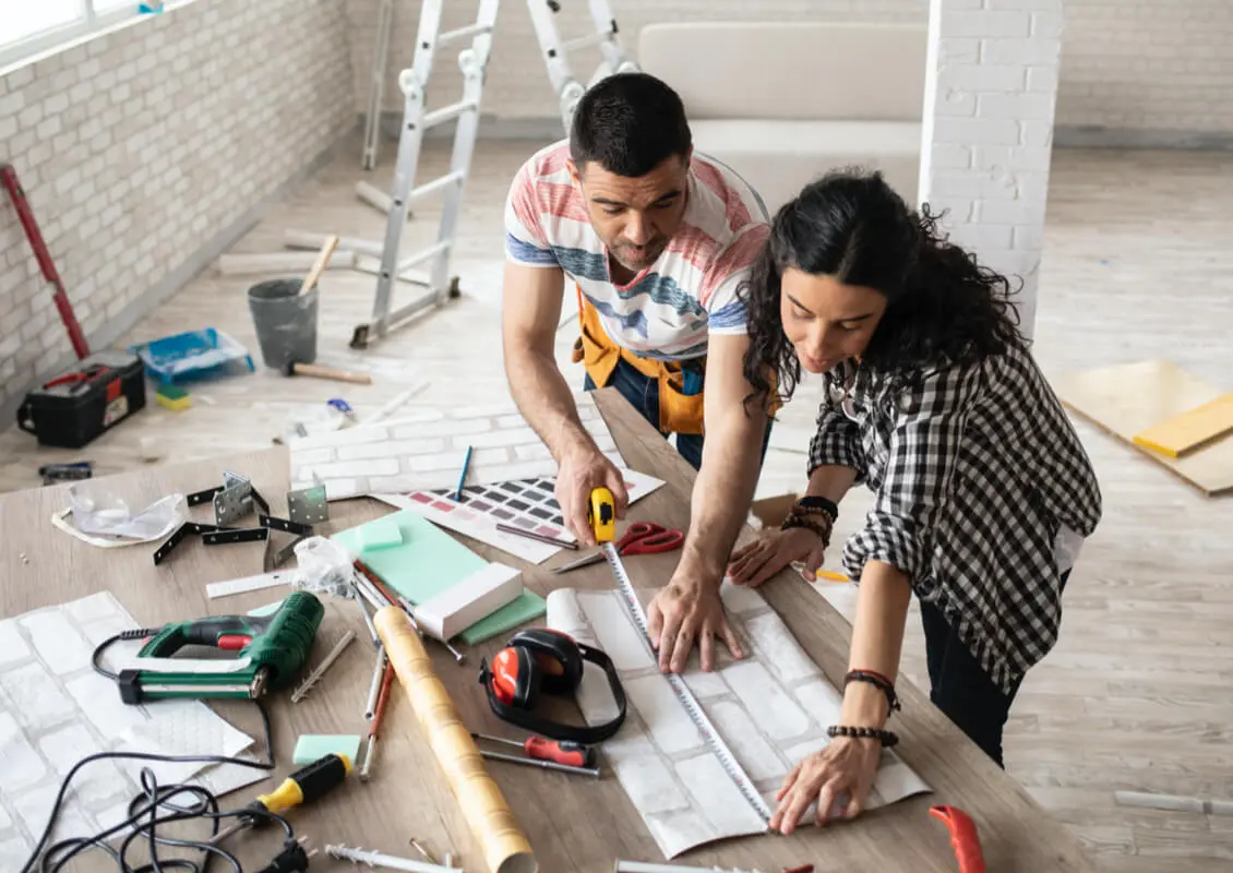 business couple measuring wallpaper