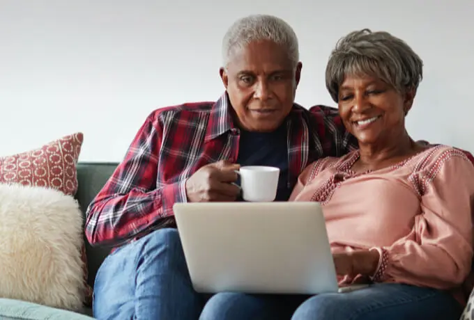 elderly couple on couch viewing laptop