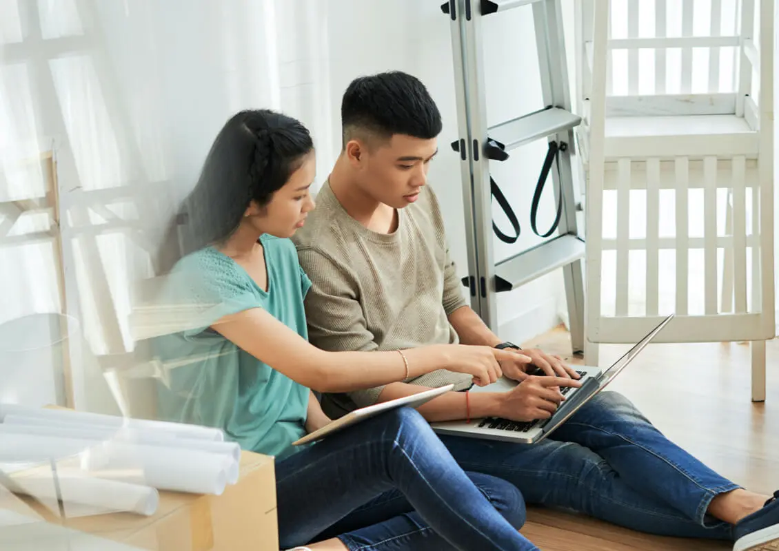 young couple sitting on floor with laptops