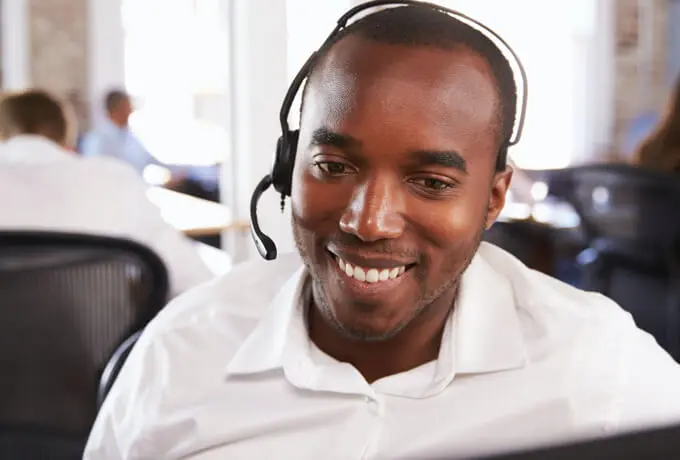 Man with phone headset smiling and assisting a customer