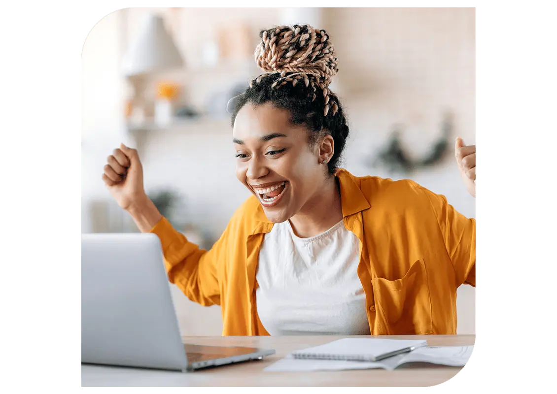 Person looking at a laptop looking excited with arms up in celebration.