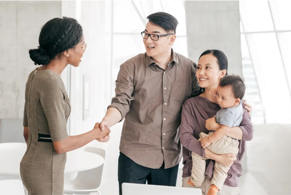 Young couple with baby shaking hands with their financial advisor